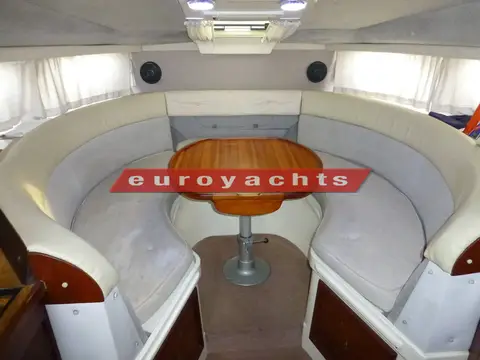 Sealine International 285: horseshoe saloon seating in pale grey upholstery around a pedestal dining table