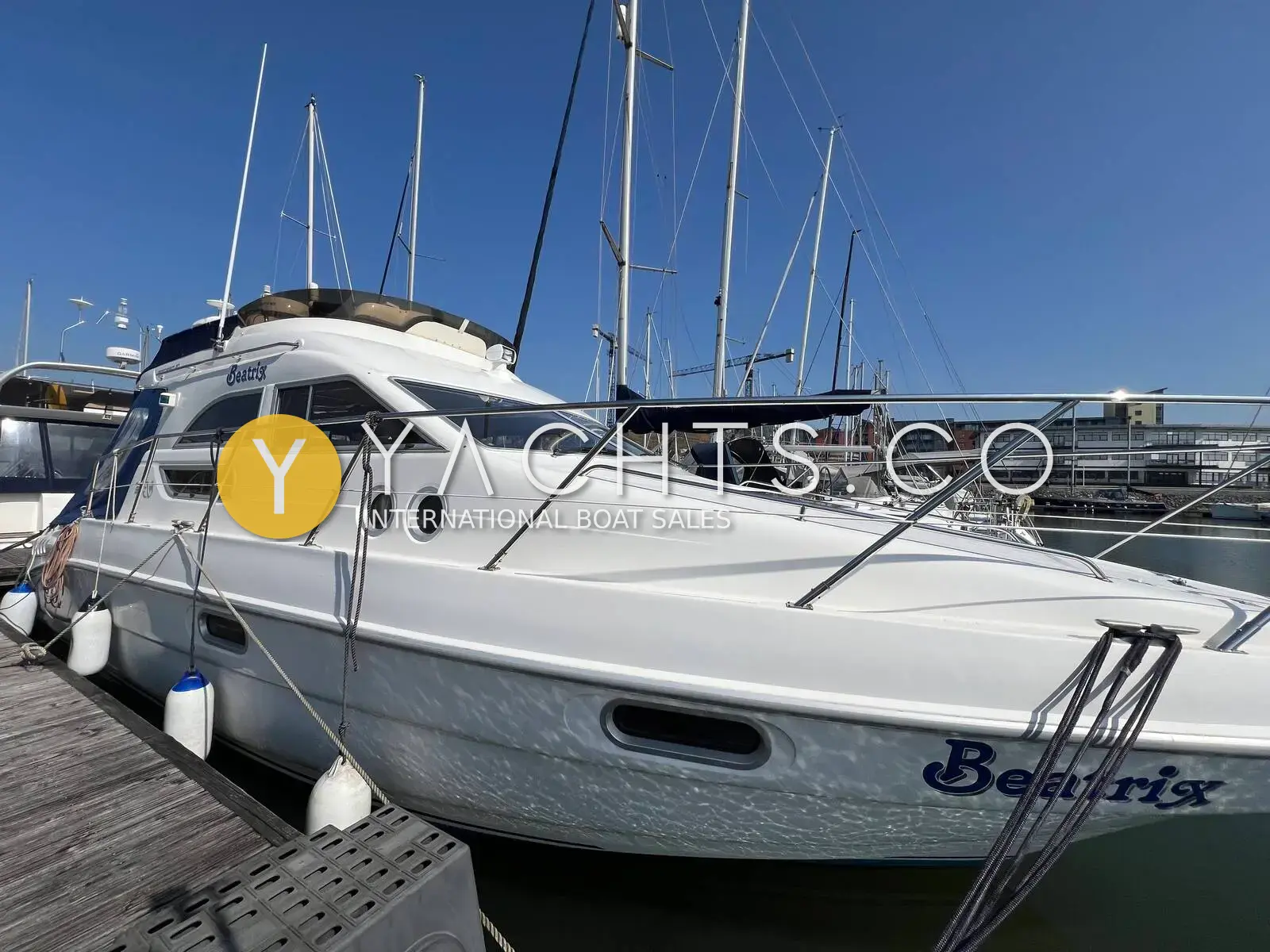 Sealine International 330 Statesman: white flybridge hull moored on a pontoon with fenders out, marina masts behind