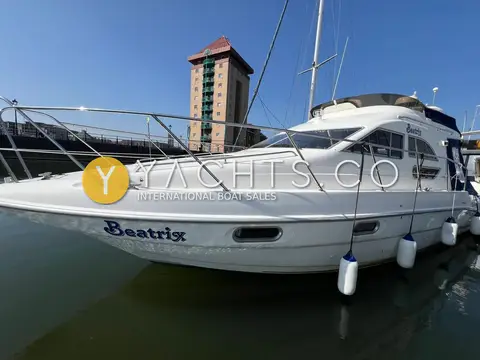 Sealine International 330 Statesman: port bow view of the white hull in the marina with a tall tower block behind