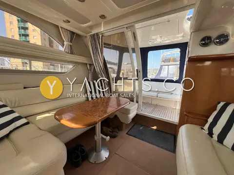 Sealine International 330 Statesman: saloon with cream seating, wooden table on stand and doors open to the cockpit