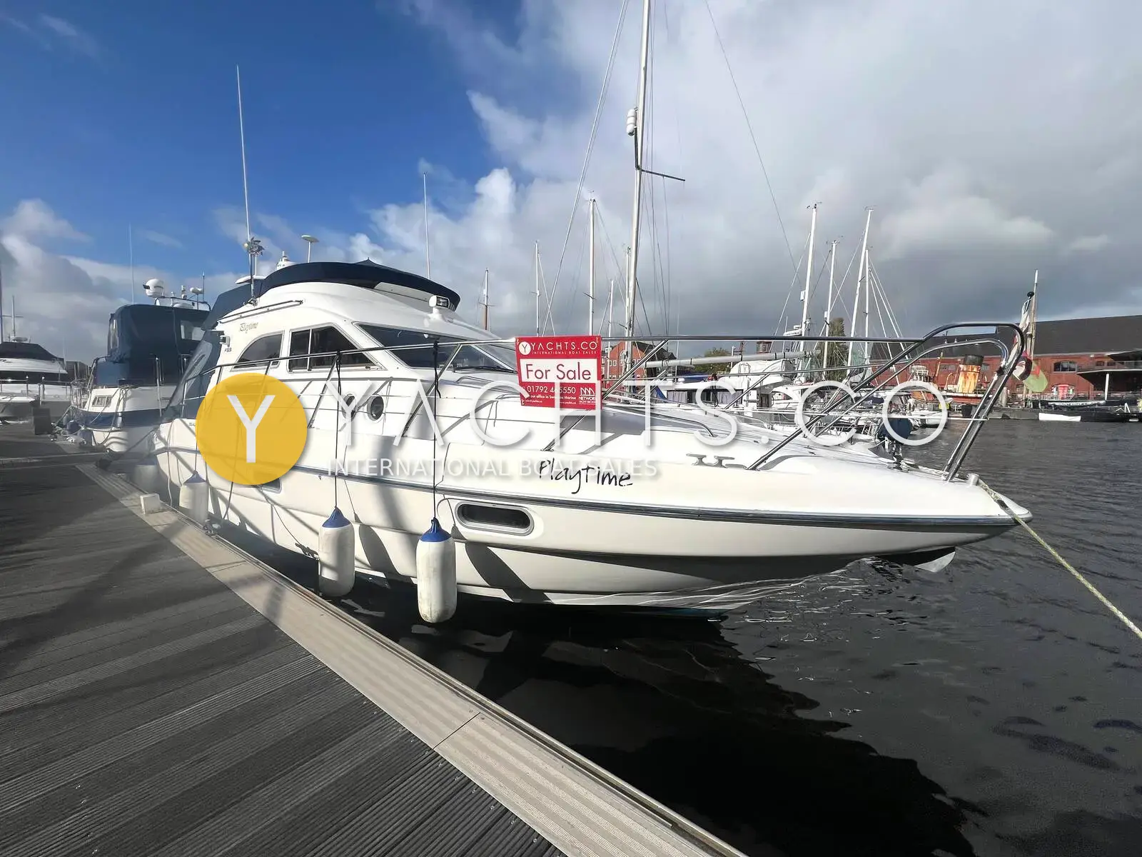 Sealine International F33: white flybridge cruiser moored alongside a marina pontoon, seen from the bow quarter