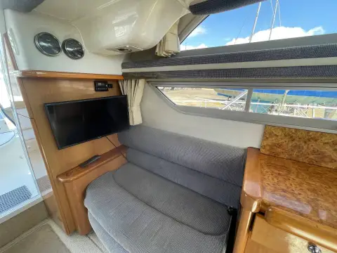 Sealine International F33: saloon corner seat with wall-mounted television and wood cabinetry