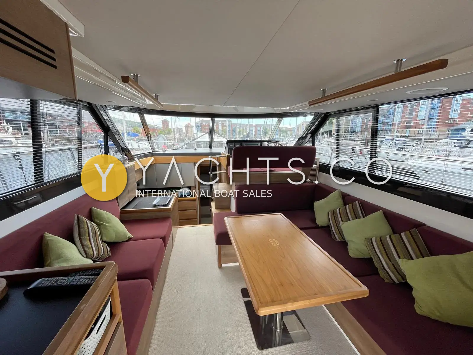 Sealine International F42: saloon looking forward to lower helm, plum upholstery, walnut table and green cushions