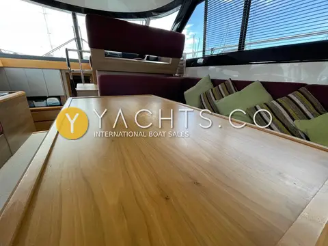 Sealine International F42: low view across walnut saloon table towards raised lower helm seat