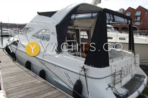 Sealine International Sealine 310/320 Statesman: starboard quarter view moored at a pontoon with black canopy enclosing the aft cockpit