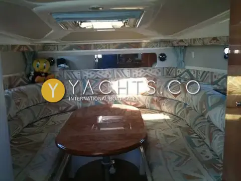 Sealine International Sealine S28 Reduced: saloon with U-shaped patterned dinette around an oval wooden table under an overhead hatch