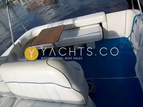 Sea Ray Sundancer 290: cockpit with white upholstered seating, wooden table and blue deck covering