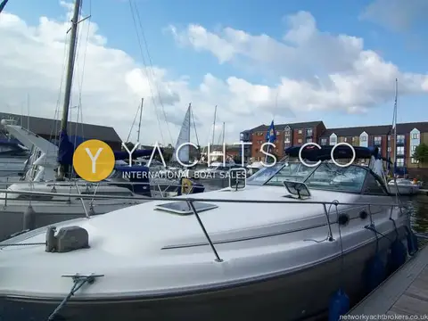 Sea Ray Sundancer 290: bow quarter view of the white hull moored on a marina pontoon with flats behind