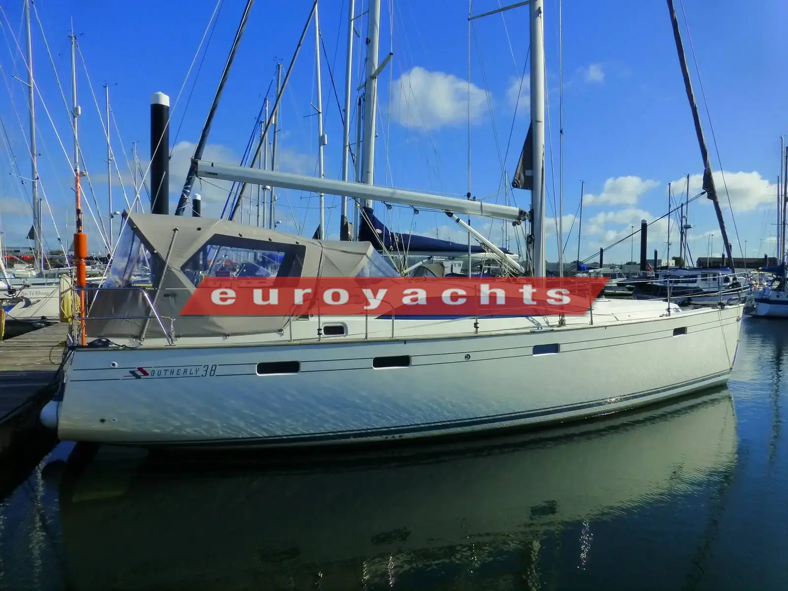 Southerly 38: white hull with blue stripe moored in marina, grey sprayhood and canopy fitted