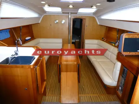 Southerly 38: saloon looking forward with cream settees, wood joinery and central drop-leaf table