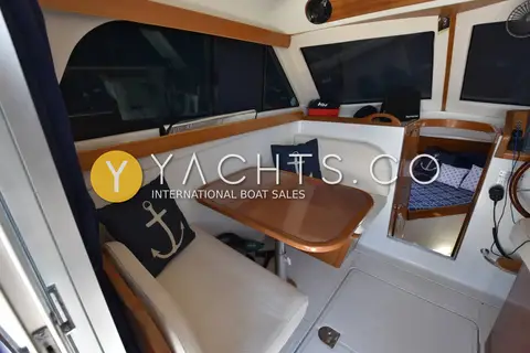 Starfisher 840: saloon dinette with cream seating, anchor cushions and varnished table beside large windows