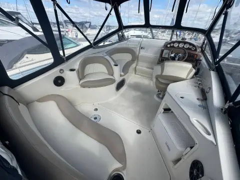 Stingray 250 CS: cockpit under the canopy with cream seating, helm seat and companionway steps