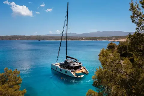 Sunreef Eco 70: catamaran at anchor in a wide blue bay with hills on the horizon