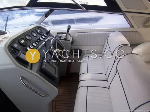 Sunseeker Martinique 36: cockpit with helm console and white piped bench seating under dark canopy