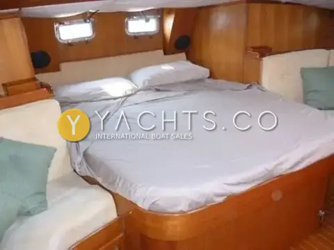 Taswell 49CC: aft owner's cabin with centreline double berth, grey bedding and warm varnished wood joinery