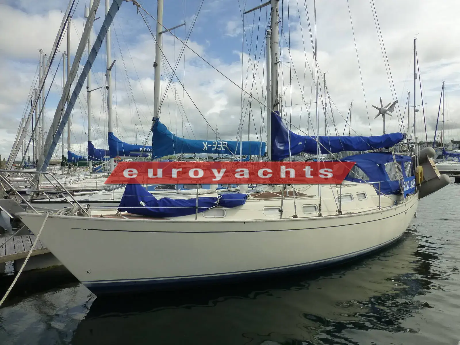 Vancouver 34: cream hull with blue sail covers, moored stern-to among yachts in a marina