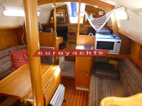 Vancouver 34: saloon looking aft with wood joinery, patterned settees, drop-leaf table and microwave