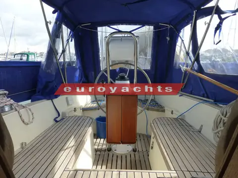 Vancouver 34: cockpit under blue bimini with teak seats, sole and wheel pedestal