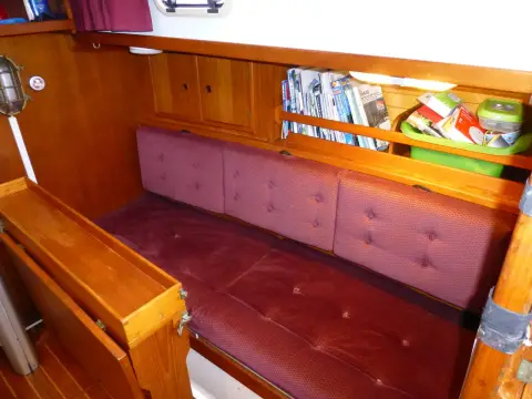 Victoria 30: saloon settee in burgundy upholstery with bookshelf and wooden locker above