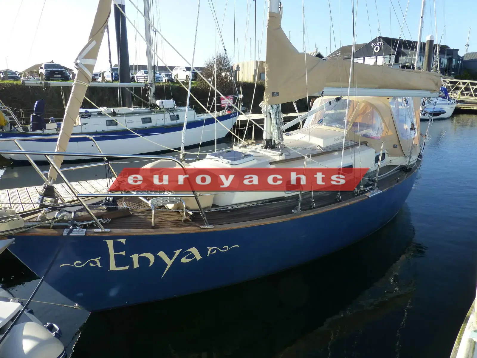 Victoria 800: blue hull with name Enya on the bow, moored in a marina with cockpit enclosure fitted