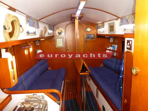 Victoria 800: saloon looking forward with blue upholstered settees, varnished wood joinery and door to forward cabin