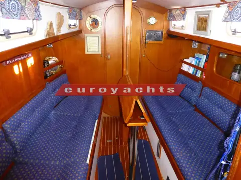 Victoria 800: saloon settees either side of folded table, wooden bulkhead and door forward