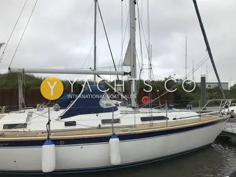 Westerly Oceanquest 35 CC: hull afloat in a walled basin, showing navy sheer stripe, boom and blue fenders