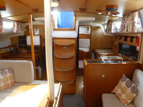Westerly Seahawk 34: saloon looking aft, ash bulkheads, companionway steps, galley to one side and patterned cushions