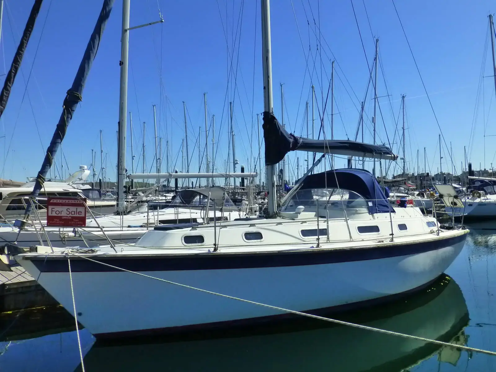 Westerly Seahawk 34: white hull afloat in a marina with blue sprayhood over the centre cockpit