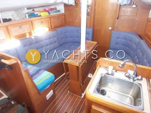Westerly Tempest: saloon with blue upholstered seating, folded teak drop-leaf table and galley sink in foreground