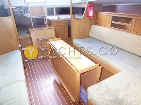 Winner 9.50: saloon looking aft to galley and companionway, folding table and striped cushioned settees